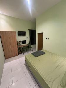 AlastuwoにあるGreen Living Homeのベッドと机とテレビのある寝室