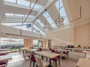 una sala da pranzo con tavoli, sedie e finestre di Lavande Hotel Shenzhen International Convention and Exhibition Center Fuhai West Subway Station a Shenzhen