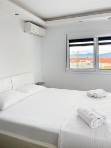 a white bedroom with a white bed and a window at Rona Vista Suites Sea view modern living in Polykhrono