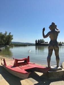 a statue of a man standing next to a red boat at Balaton Vendégház Keszthely in Keszthely +5 photos
