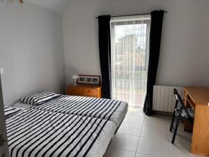 a bedroom with two beds and a window with a desk at La Cambuse in Saint-Germain-sur-Ay
