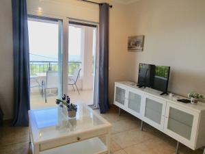 a living room with a tv and a table with a tv stand at Barbati Beach Apartments in Barbati