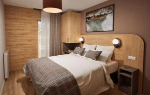 una habitación con una cama grande con sábanas y almohadas blancas en Hotel L'Ecrin Blanc by Odalys, en La Rosière