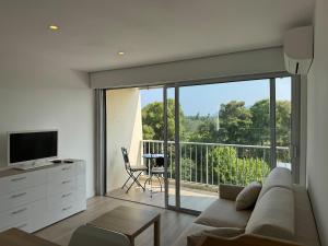 a living room with a couch and a tv and a balcony at Beautiful river view studio in Mandelieu-La Napoule