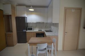 Polisi i VogëlにあるKaja Apartments ' Studio 'のキッチン(木製テーブル、白い椅子付) +6枚の写真
