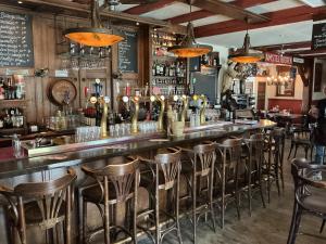 a bar with a row of stools in a restaurant at De Toerist Thuis Bij De Sluis in Spaarndam