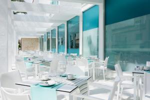 MarSenses Puerto Pollensa Hotel & Spa في بورت دي بوينسا: مطعم بطاولات بيضاء وكراسي بيضاء
