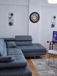 a living room with a couch and a clock on the wall at Aurora's Apartment Shkoder in Shkodër