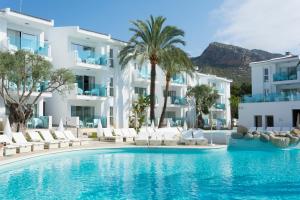 a pool in front of a hotel with white buildings at MarSenses Puerto Pollensa Hotel & Spa in Port de Pollensa