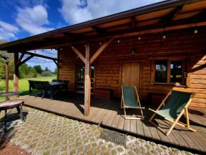 a wooden deck with chairs and a table and a cabin at Domek Jaśminowy, Domek z SAUNĄ in Brzozie