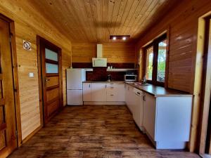 a kitchen with white appliances in a wooden cabin at Domek Jaśminowy, Domek z SAUNĄ in Brzozie