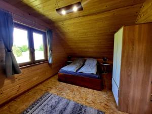 a small room with a bed in a log cabin at Domek Jaśminowy, Domek z SAUNĄ in Brzozie