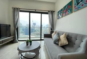 a living room with a couch and a large window at Lucentia Residences BBCC LaLaport in Kuala Lumpur