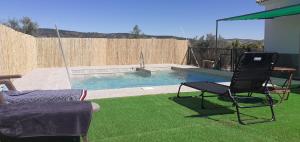 a backyard with a pool with two chairs and a table at Cortijo Rural Buenavista Montefrio in Montefrío