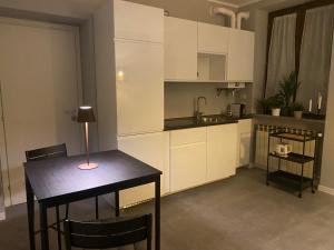 a kitchen with white cabinets and a table with a lamp at B&Bi13 in Magenta