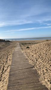 a wooden path through the sand on a beach at Apartamento Delfin - Punta Umbria in Punta Umbría