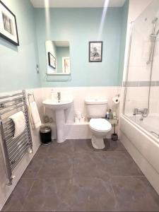 a bathroom with a toilet and a sink and a tub at Chichester City Centre 2 Bedroom Flat I Ground Floor with Underground Parking I Chichester Holiday Properties in Chichester
