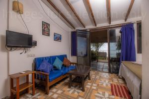 a living room with a blue couch and a tv at Deepiksha Beach Resort Talpona in Magdāl
