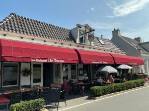 a restaurant with people sitting at tables outside of it at De Toerist Thuis Bij De Sluis in Spaarndam