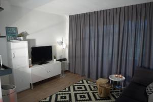 un salon avec une télévision sur un meuble blanc dans l'établissement Amelander Kaap 101, à Hollum