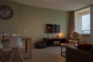 sala de estar con TV, mesa y silla en Strand166, en Egmond aan Zee