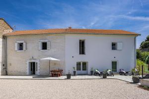a white house with a table and an umbrella at Lara Holiday Home in Kanfanar