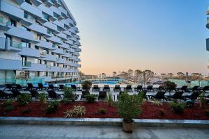 a building with chairs and a pool in front of it at Ricky Apartment in Infinity Spa & Pool in Mamaia Sat/Năvodari