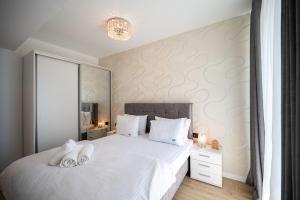 a bedroom with a bed with two white towels on it at Ricky Apartment in Infinity Spa & Pool in Mamaia Sat/Năvodari +30 photos