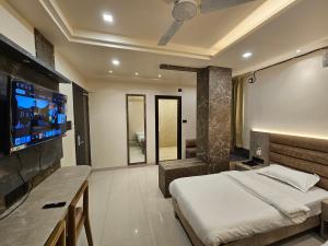 a bedroom with a bed and a flat screen tv at The Monarch Hotel By Birina in Jorhāt