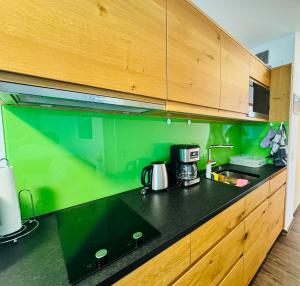 ティティゼー・ノイシュタットにあるMichels Apartmentの緑の壁と黒いカウンタートップが備わるキッチン +16枚の写真