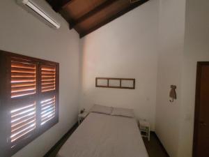 um quarto branco com uma cama e uma janela em Casa das Cores em Pirenópolis