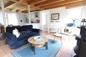 Una sala de estar con un sofá azul y una mesa. en Am Wall 16 - Ferienhaus, en Langeoog