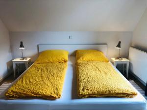 1 dormitorio con 2 camas, mantas amarillas y lámparas en Am Wall 16 - Ferienhaus, en Langeoog