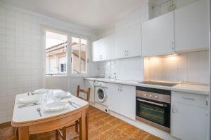 a kitchen with white cabinets and a table and a sink at Eguzkilore - baskeyrentals in Lekeitio