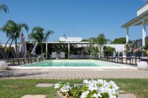 a swimming pool with chairs and flowers in a yard at VILLA LEONARDO SAN FOCA - Room, Pool & Restaurant in San Foca