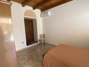 a bedroom with a bed and a chair in a room at MICHI Holiday Home Tortolì in Tortolì