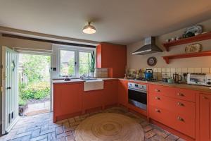 a kitchen with red cabinets and a window at Bertie's Cottage by Keepers Cottages in Robertsbridge