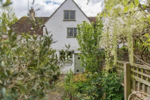 a white house with a fence and trees at Bertie's Cottage by Keepers Cottages in Robertsbridge