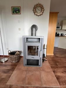 une cheminée dans un salon avec une horloge au mur dans l'établissement Haus Waldzeit, inclusief bedlinnen handdoeken en eindservice, à Frankenau