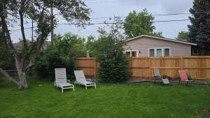 a yard with three chairs and a fence at Alanas house in Denver