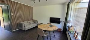 a living room with a table and a couch at Bungalow Hartje Veluwe in Otterlo