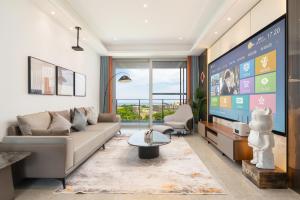 a living room with a couch and a tv at 三亚海棠湾蔚蓝海湾公寓 in Sanya