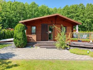 a small wooden cabin with a porch in a garden at Domek letniskowy w Nadolu nad jeziorem Żarnowieckim in Nadole