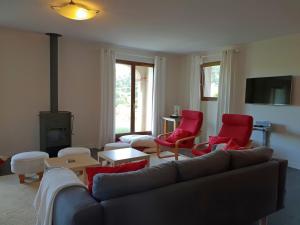 a living room with a couch and red chairs at Villa with heated pool, jacuzzi, sports field and stunning views in Montbrun-des-Corbières