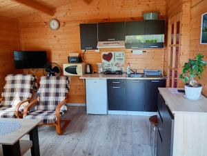 a kitchen in a wooden cabin with two chairs at Domek letniskowy w Nadolu nad jeziorem Żarnowieckim in Nadole