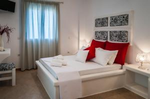 a bedroom with a large white bed with red pillows at Oceanis Rooms in Adamas