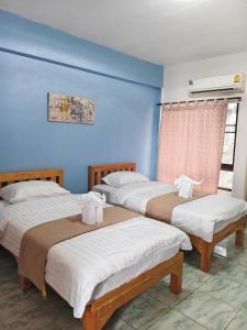 two beds in a room with blue walls at Noble Thippanate in Chiang Mai