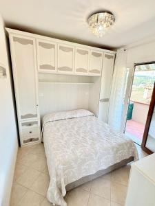 a bedroom with a bed and white cabinets and a chandelier at Isabel Apartment in Porto Azzurro