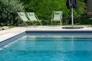 two chairs and an umbrella next to a swimming pool at Maison Le Garochet in Digoin