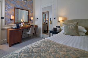 ein Hotelzimmer mit Bett, Schreibtisch und Spiegel in der Unterkunft Sloane Square Hotel in London + 47 Fotos
